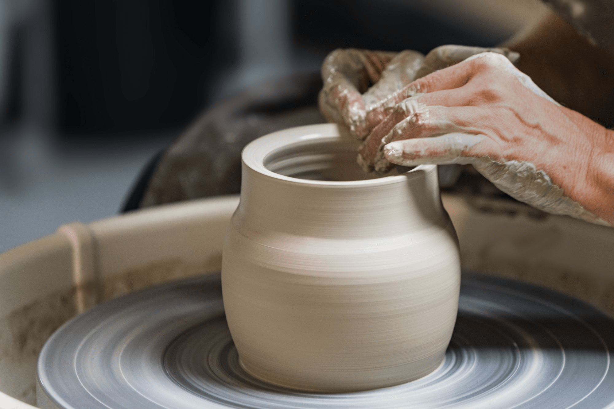 Close up shot of hands creating a pot on a pottery wheel