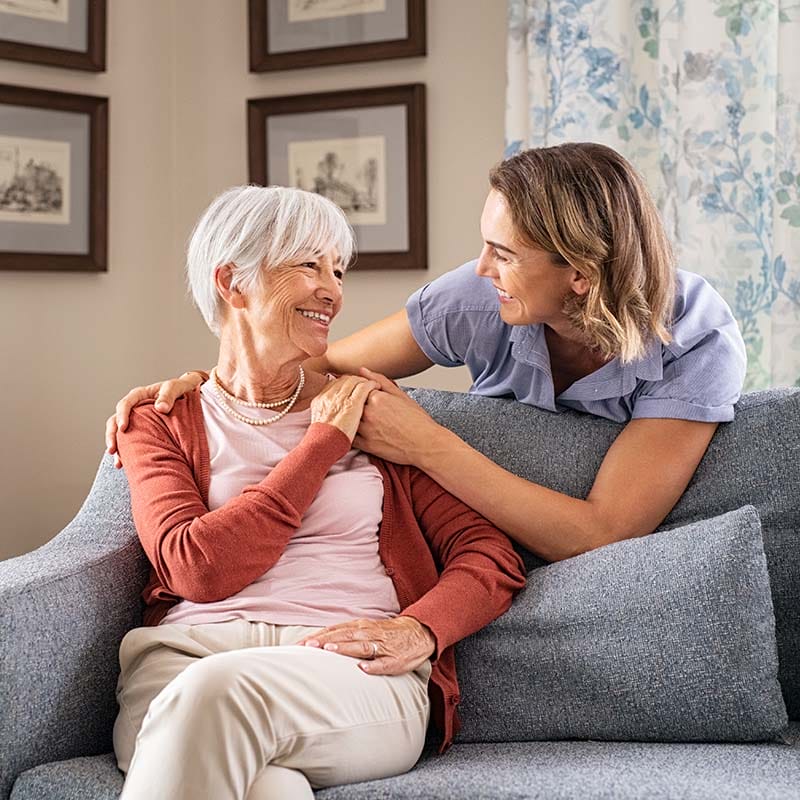 Portrait Photo of Senior Couple Hugging and Laughing while sitting on a Couch at Stellar Living Communities