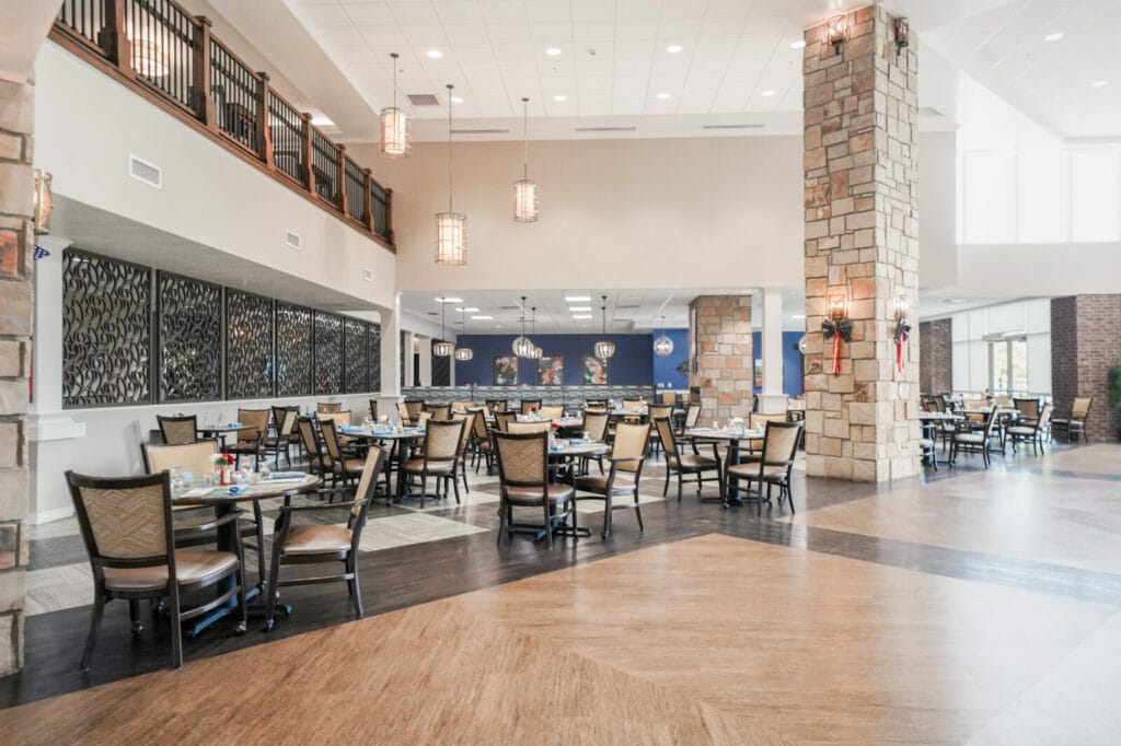 Creekside Senior & Assisted Living Dining Room, featuring two-story ceilings, modern decor, and herringbone hardwood floors.