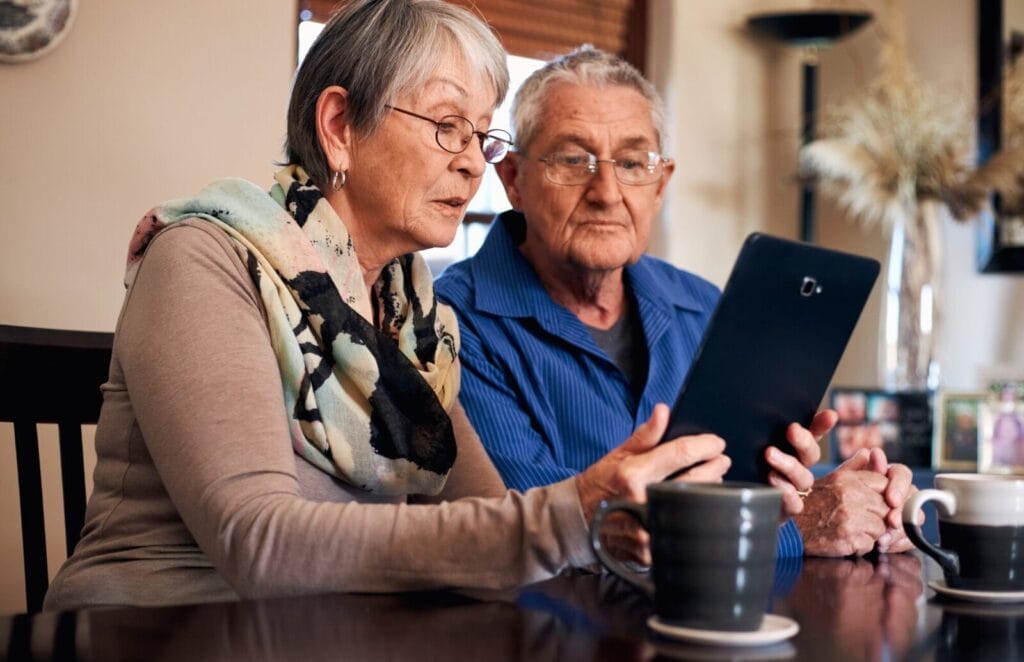 Two seniors consult a tablet.