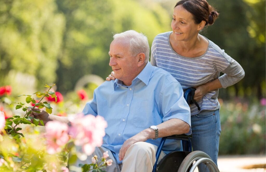 A woman pushes a senior man in a wheelchair.