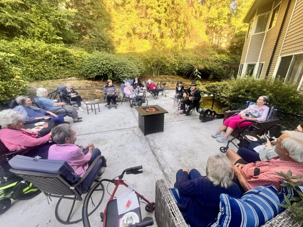Seniors enjoy natural beauty outdoors around a fire pit.