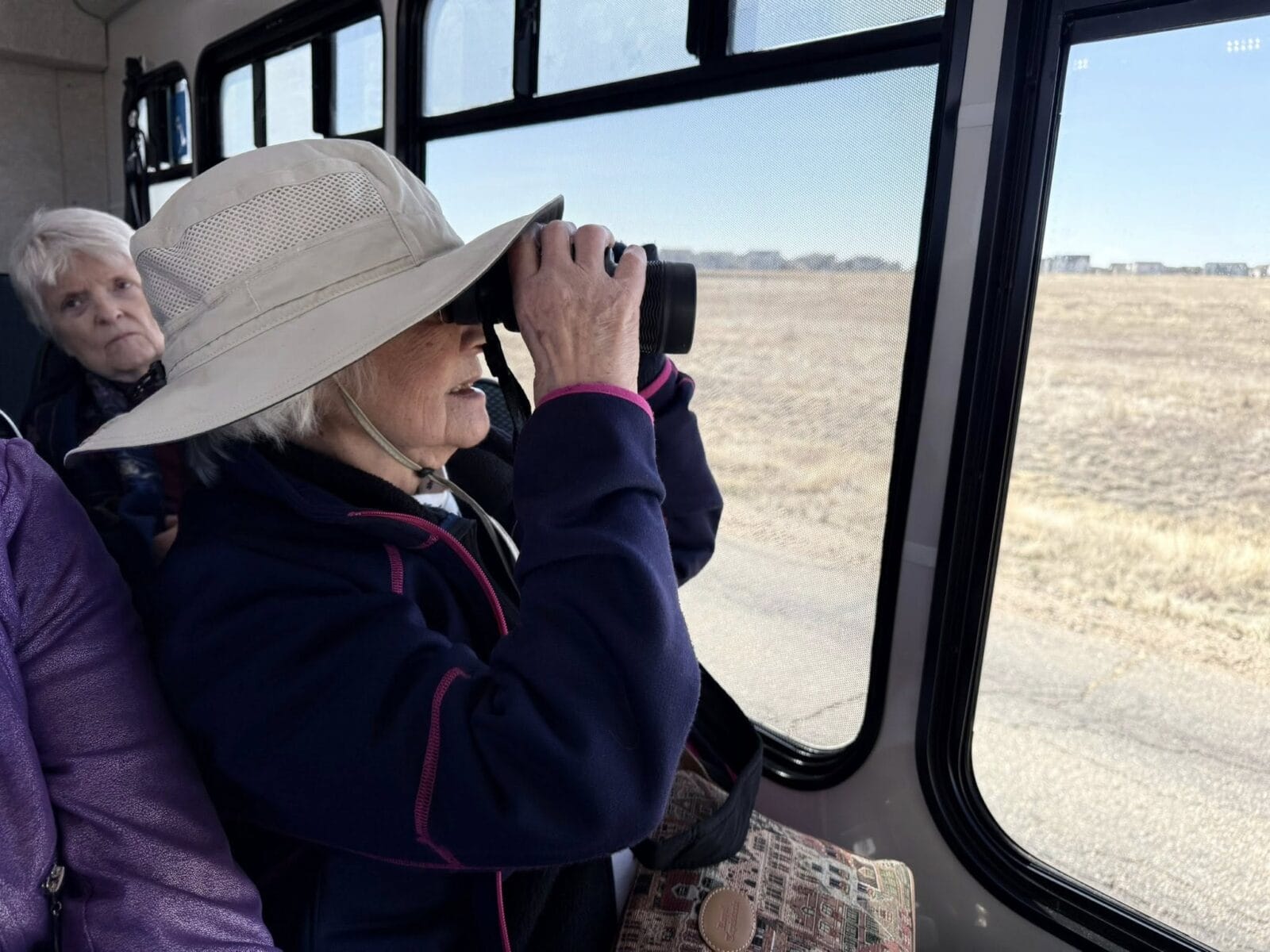 Senior at Acoya Cherry Creek looking through binoculars at wildlife.