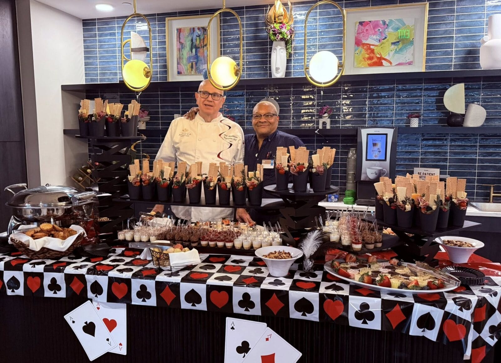 Acoya Cherry Creek chef and staff member in front of a poker-themed table of snacks