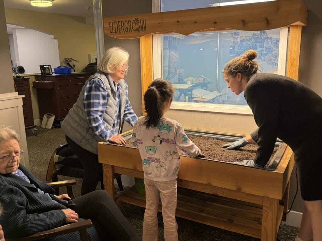 A child, mom, and grandma work to replant a box